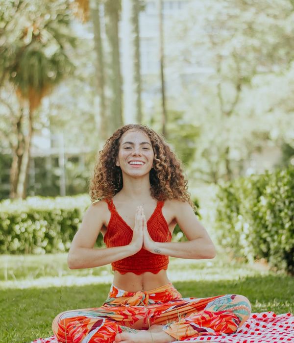 Smiling woman stretching gently on a yoga mat outdoors.